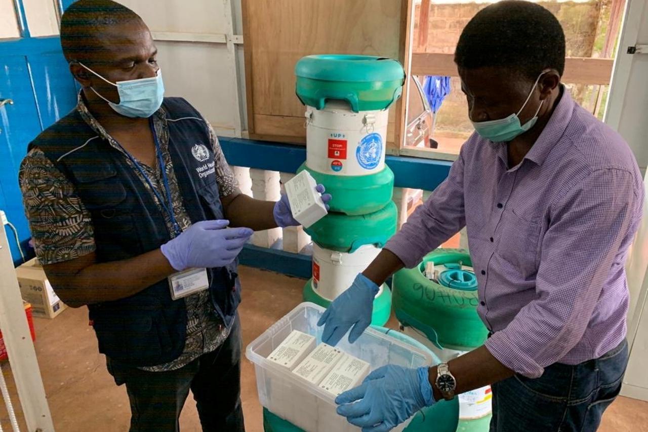 Workers from the World Health Organization inspect Ebola vaccines stored in an Arktek ultra-cold vaccine storage cylinder seen in the background in Mbandaka