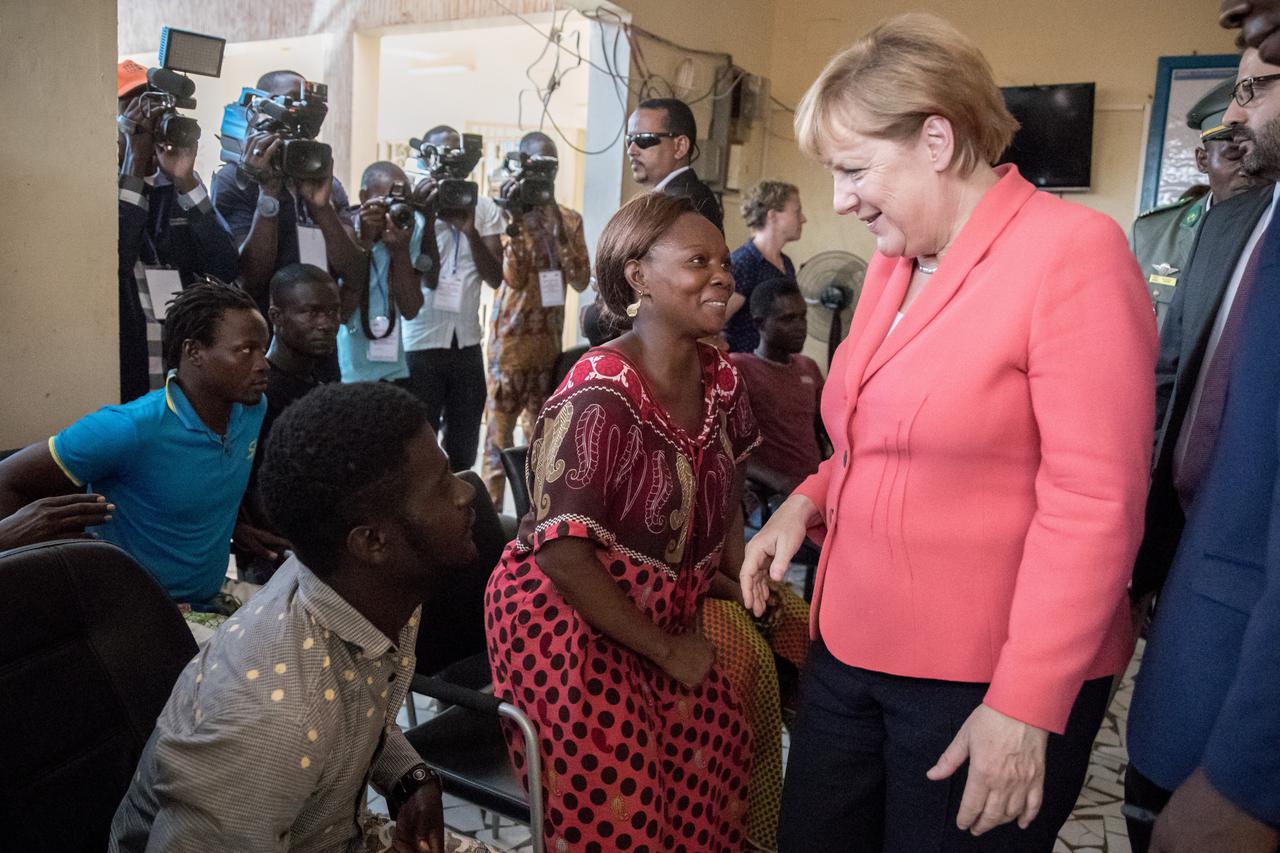 German Chancellor Angela Merkel (CDU) inside a reception and transit center for migrants of the International Organization for Migrants (IOM) speaking with refugees such as Liberian Binta (M) in Niamey, Niger, 10 October 2016. Chancellor Merkel is on a th