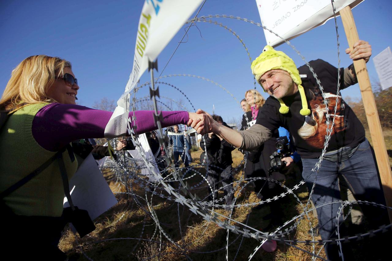 Women shake hands through razor wire during a protest against barbed wire fences along the border crossing between Slovenia and Croatia in Brezovica pri Gradinu, Slovenia December 19, 2015. REUTERS/Srdjan Zivulovic