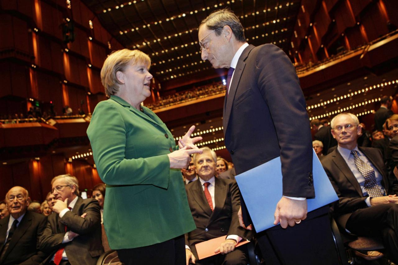 'German Chancellor Angela Merkel (L) talks to new European Central Bank (ECB) President Mario Draghi prior to a farewell ceremony for outgoing ECB President Jean-Claude Trichet (C, in background) prio