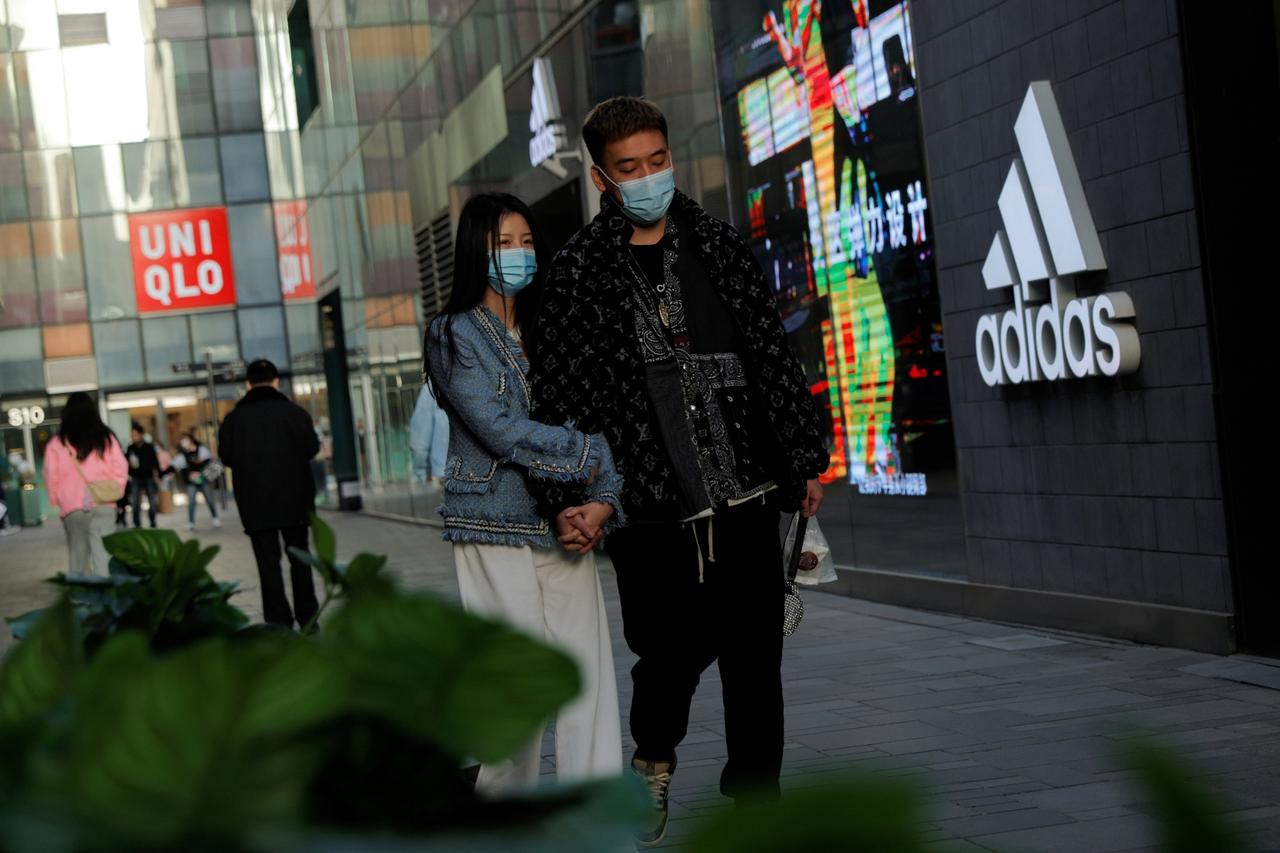 FILE PHOTO: People walk past an Adidas store in a shopping area in Beijing
