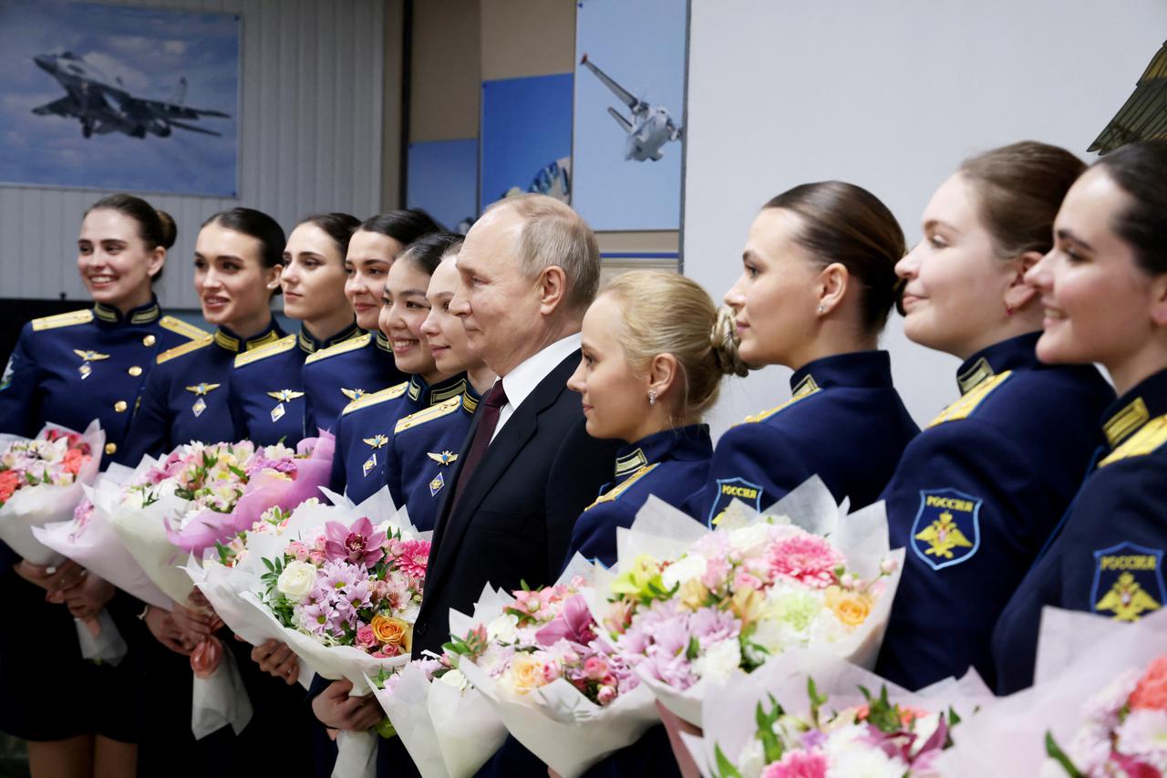 Russian President Vladimir Putin poses for a photo with female graduates of the Higher Military Aviation School of Pilots named after Hero of the Soviet Union A.K. Serov in Krasnodar