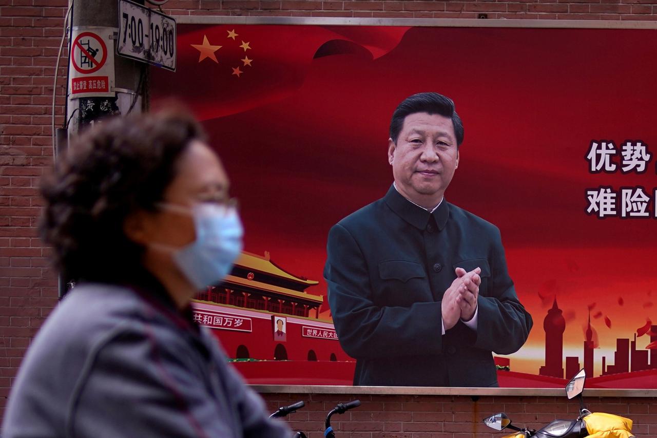FILE PHOTO: Woman is seen past a portrait of Chinese President Xi in Shanghai