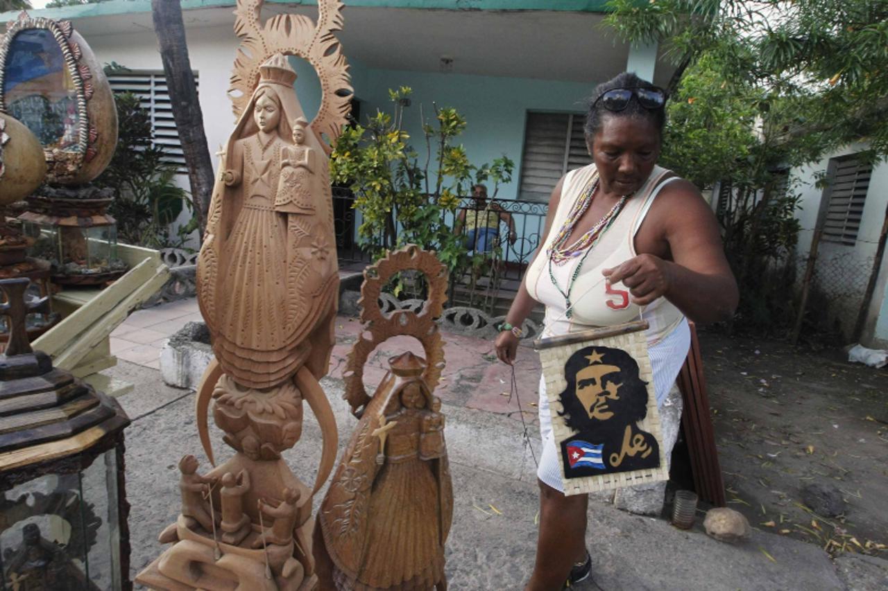 'A vendor of religious icons related to the Virgin of Charity of El Cobre arranges her display for the throngs of Catholic faithful expected to arrive for next week\'s visit by Pope Benedict, at the e
