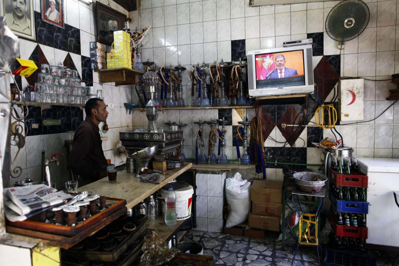 'An Egyptian man working at a traditional coffee shop watches on TV President Mohamed Morsi take the oath of office in Cairo on June 30, 2012 to become Egypt\'s first freely elected leader and its fir