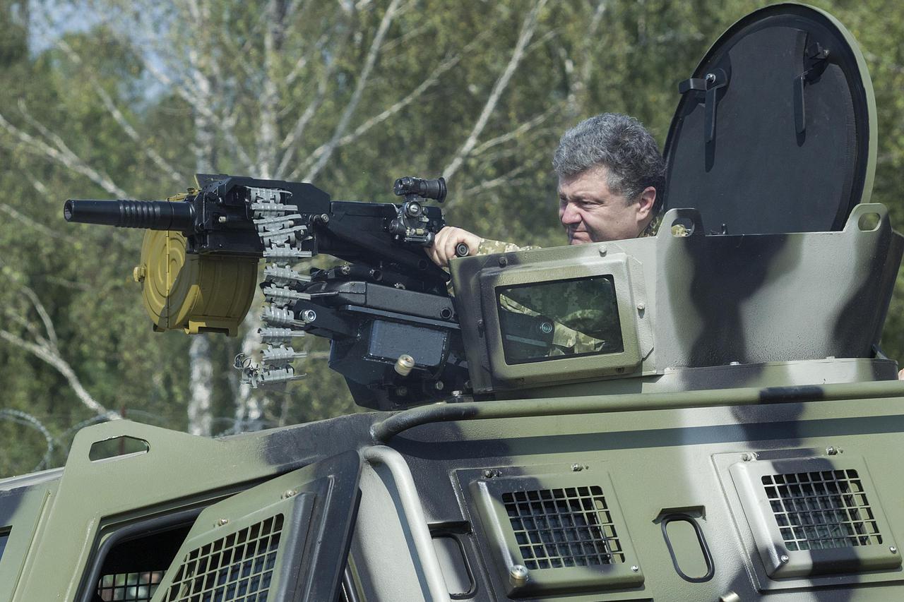 Ukraine's President Petro Poroshenko aims the weapon of an armoured vehicle during his visit to a demonstration of new weapons for the Ukrainian armed forces at a military base outside Kiev July 26, 2014. Picture taken July 26, 2014. REUTERS/Mykhailo Mark