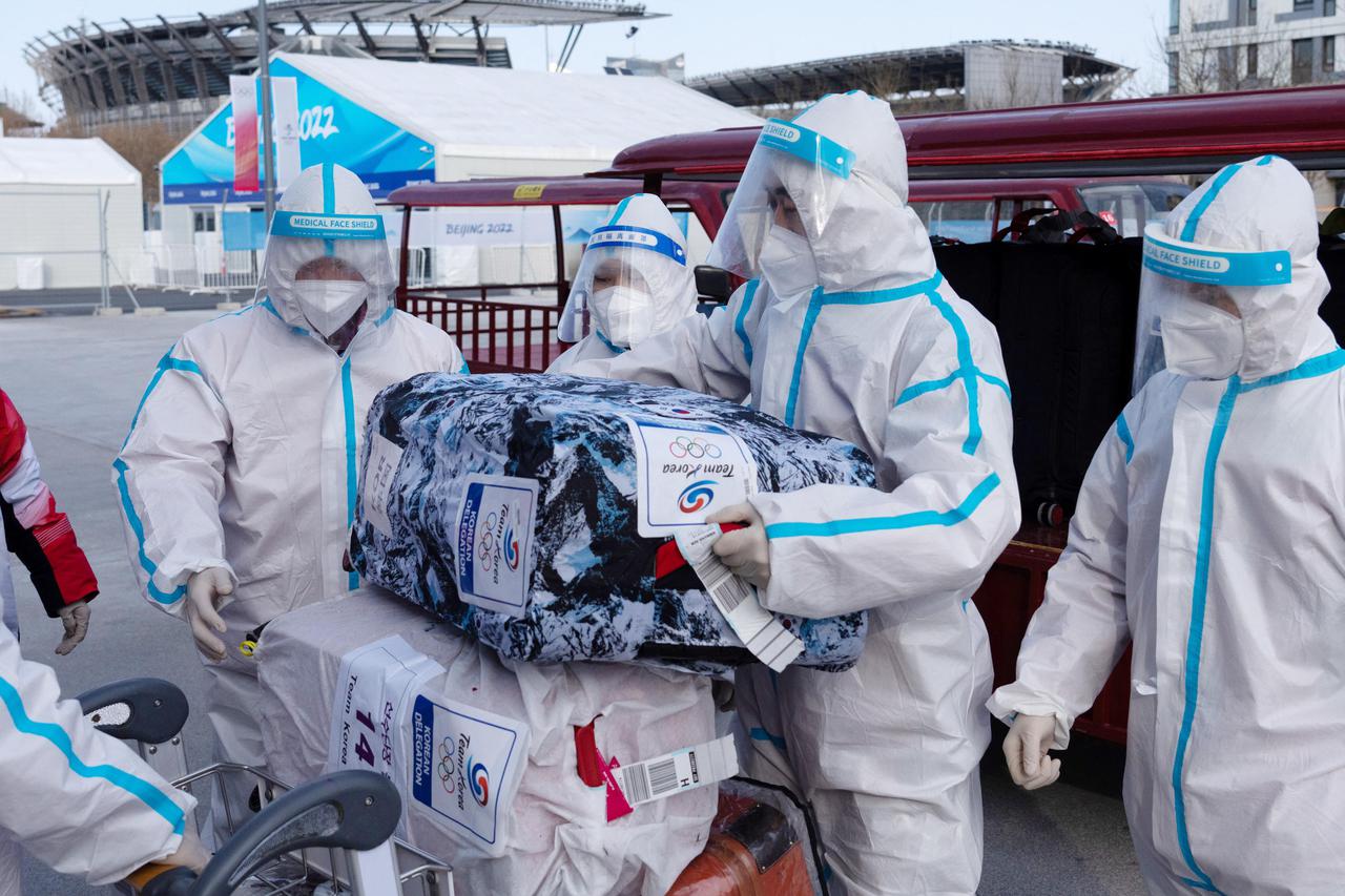 People wearing personal protective equipment (PPE), designed to prevent the spread of the coronavirus disease (COVID-19), load baggage belonging to members of South Korea