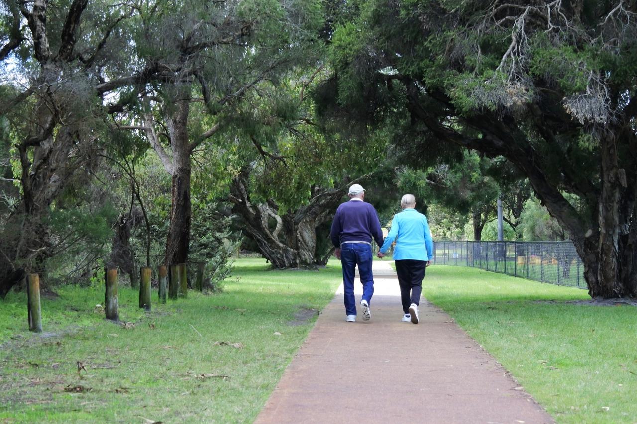 Active senior couple holding hands walking together in he park
