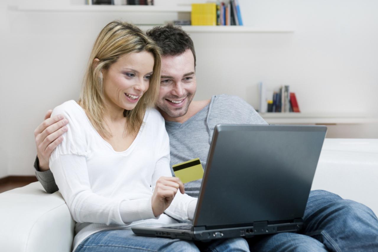 'Young couple doing shopping in internet with credit card at home'