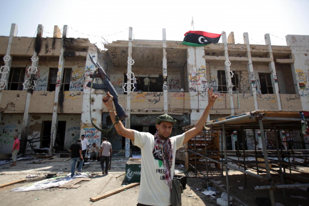 'TOPSHOTS A Libyan rebel celebrates at Moamer Kadhafi\'s former Bab al-Aziziya headquarters in Tripoli on August 27, 2011, as fighting was still under way on various fronts in Libya, with the insurgen