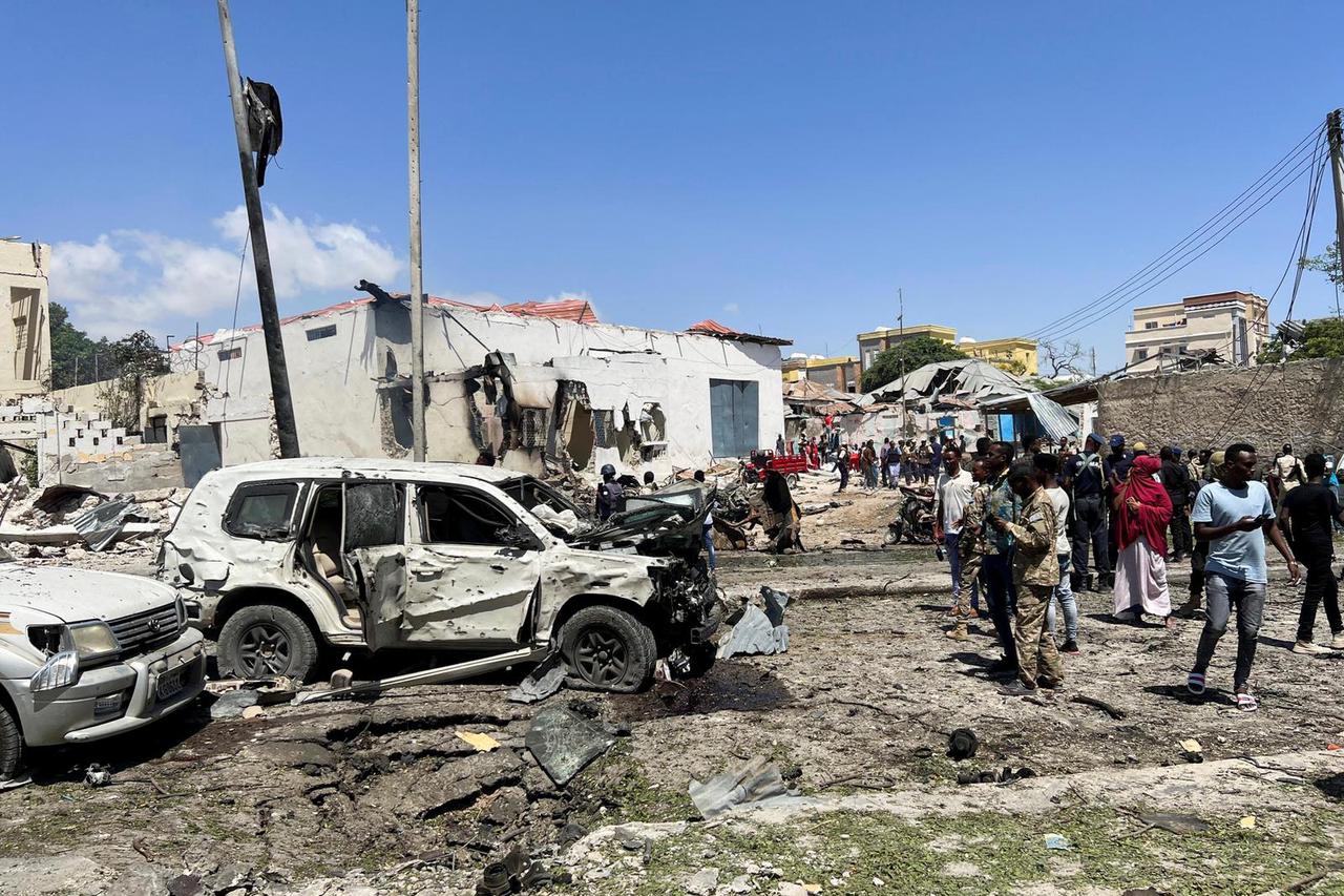 Civilians look at the wrecked vehicles at the scene of an explosion in the Hamarweyne district of Mogadishu