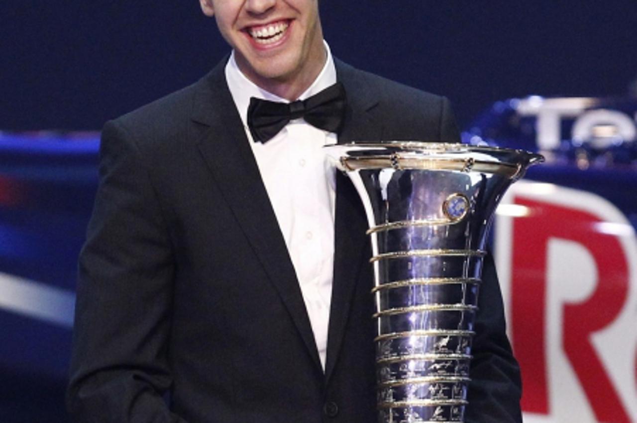 'Red Bull Formula One driver Sebastian Vettel of Germany poses with his FIA trophy during the 2011 Federation Internationale de l\'Automobile (FIA) gala night in Gurgaon on the outskirts of New Delhi 