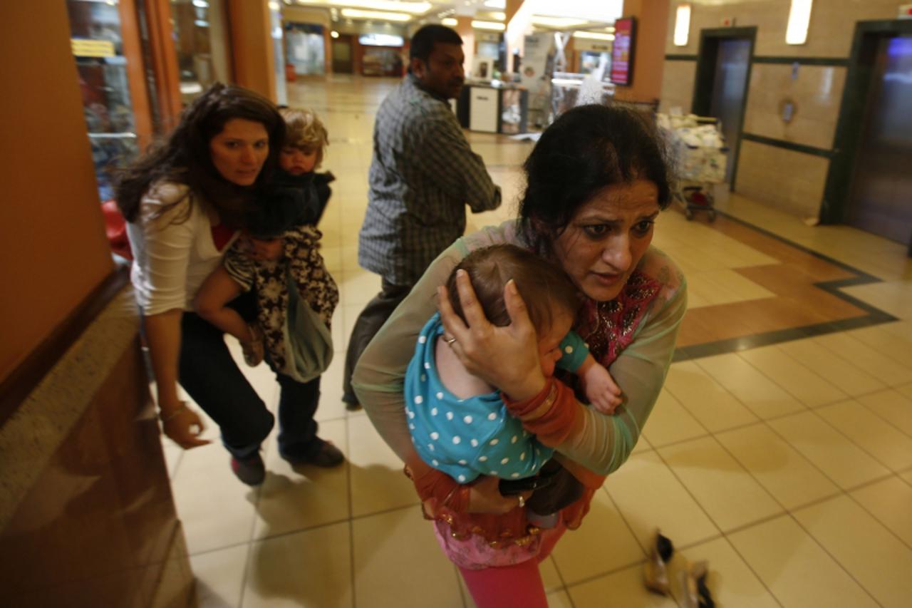 'Women carrying children run for safety as armed police hunt gunmen who went on a shooting spree in Westgate shopping centre in Nairobi September 21, 2013. The gunmen stormed the shopping mall in Nair
