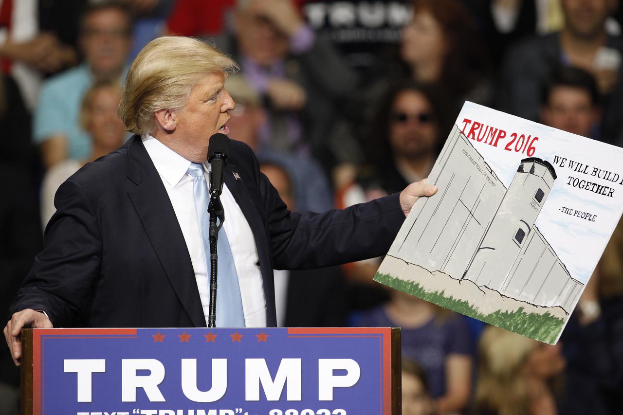 U.S. Republican presidential candidate Donald Trump holds a sign supporting his plan to build a wall between the United States and Mexico that he borrowed from a member of the audience at his campaign rally in Fayetteville, North Carolina March 9, 2016. T