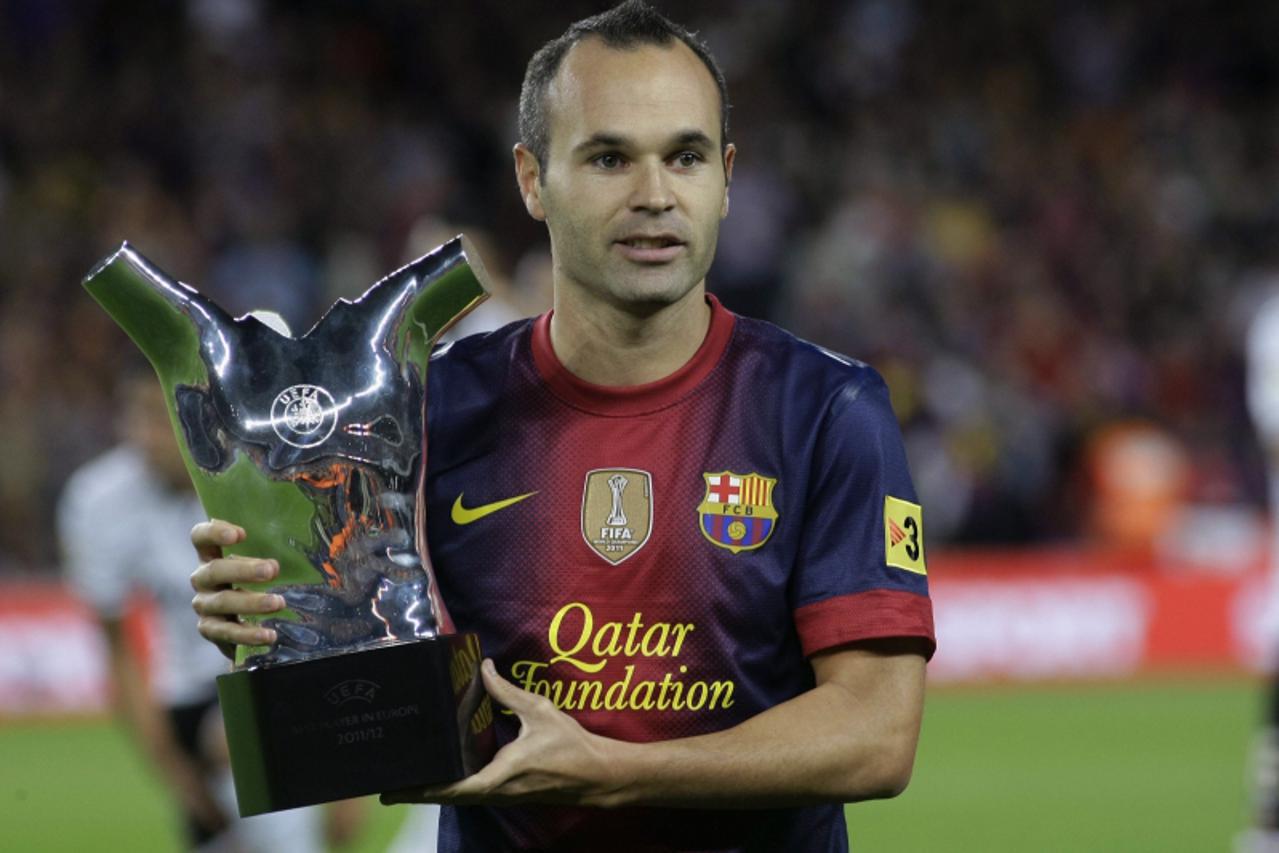 'Barcelona's Andres Iniesta holds up the UEFA trophy for the Best Player in Europe before his team's Spanish first division soccer match against Valencia at Nou Camp stadium in Barcelona September 2