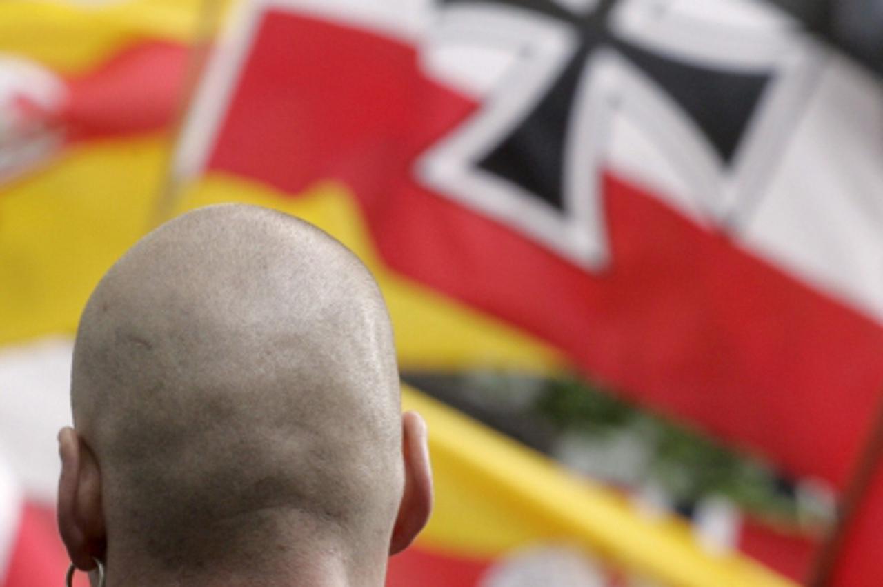 'A demonstrator of the neo-Nazi National Democratic Party (NPD) is seen in front of  flags during a rally to commemorate the 60th anniversary of the surrender of Nazi Germany in Berlin 08 May 2005.   