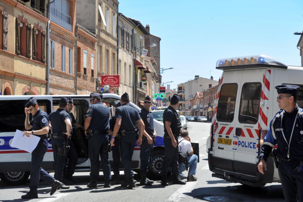 'French policemen stand near a bank (unseen) where four people have been taken hostage by a man claiming to be linked to al-Qaeda in the southern French city Toulouse on June 20, 2012. The man fired a
