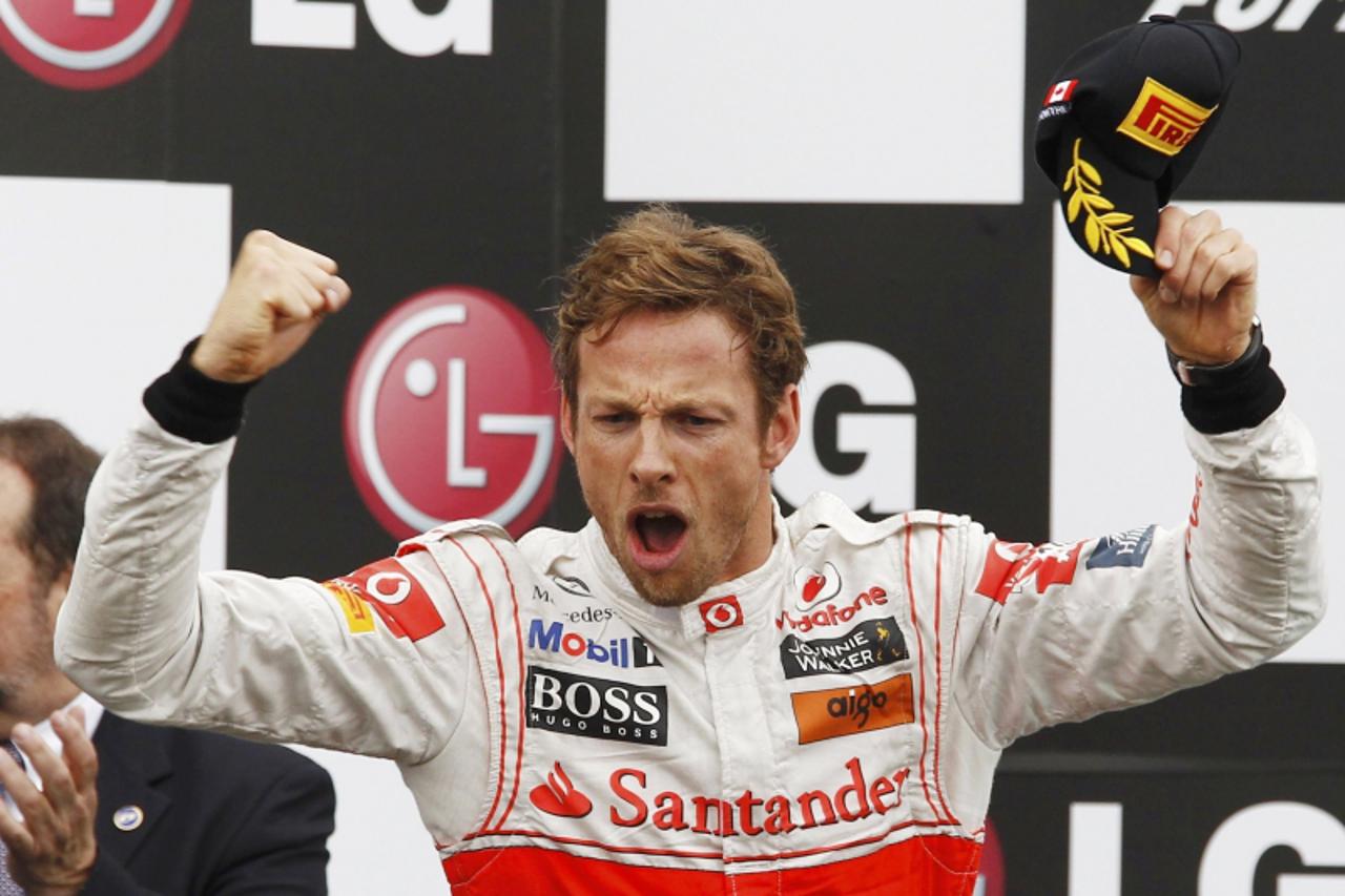 'McLaren Formula One driver Jenson Button of Britain celebrates winning the Canadian F1 Grand Prix on the podium at the Circuit Gilles Villeneuve in Montreal June 12, 2011.   REUTERS/Chris Wattie (CAN