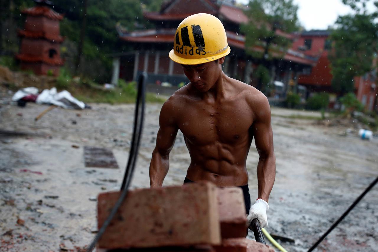 The Wider Image: Brick carrier builds social success Worker Shi Shenwei pulls a wheelbarrow at the construction site of a Buddhist temple in the village of Huangshan, near Quanzhou, Fujian Province, China, September 28, 2016. REUTERS/Thomas Peter         