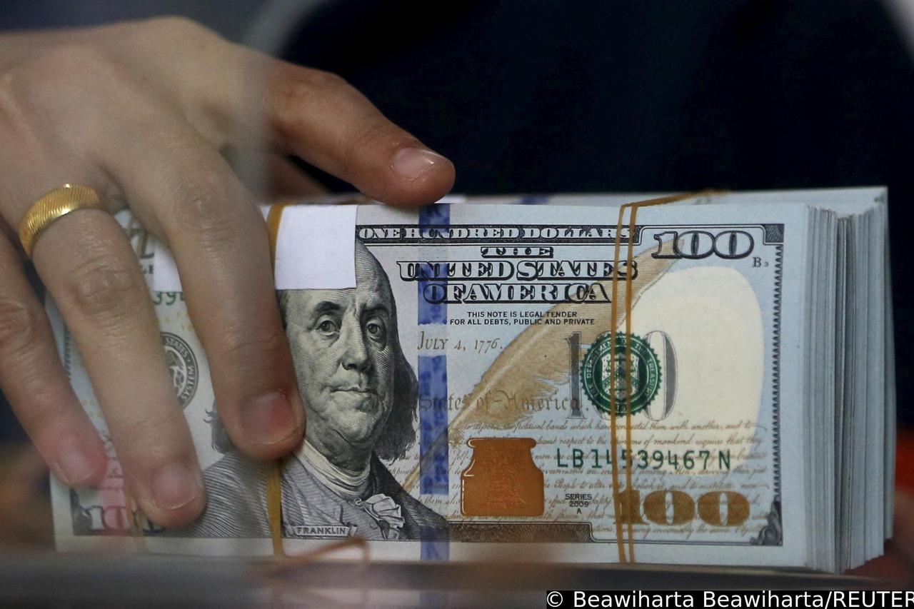 FILE PHOTO: An employee of a money changer holds a stack of U.S. dollar notes before giving it to a customer in Jakarta