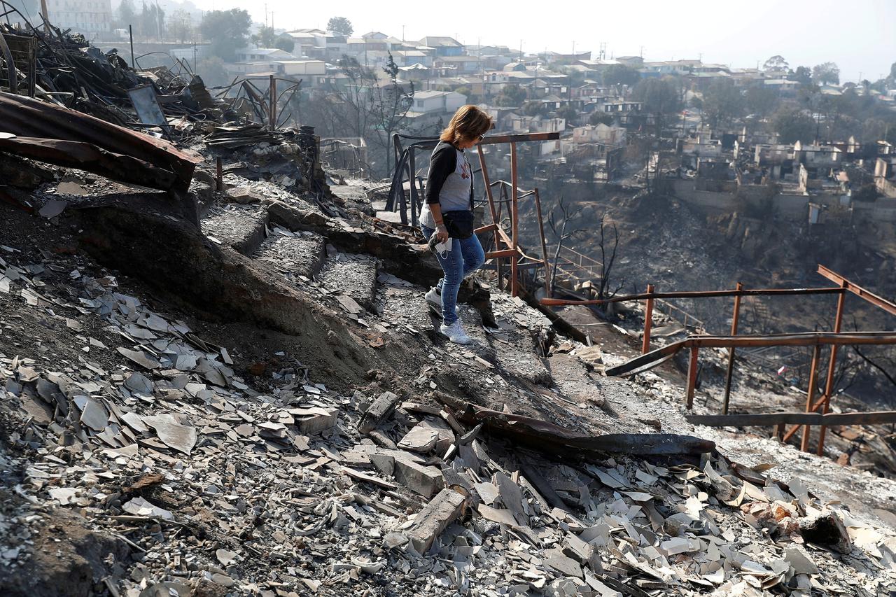 Ingrid Crespo walks on the remains of her house burned, following the spread of wildfires in Vina del Mar
