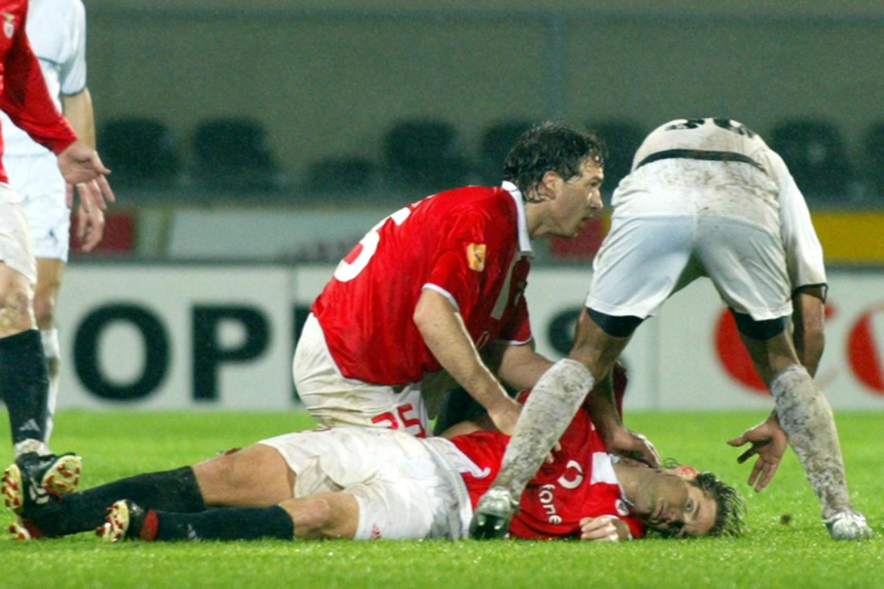 'Benfica player Sokota (C) and Guimaraes Cleber (R) help Benfica\'s Hungarian soccer striker Miklos Feher (down) during the Portuguese Premier League match held at Guimaraes stadium 25 January 2004. H