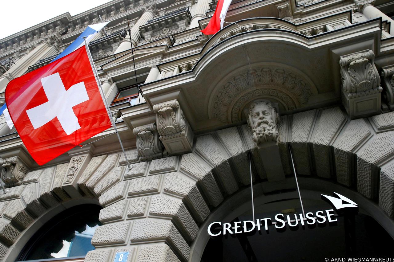 FILE PHOTO: Switzerland's national flag flies below a logo of Swiss bank Credit Suisse in Zurich