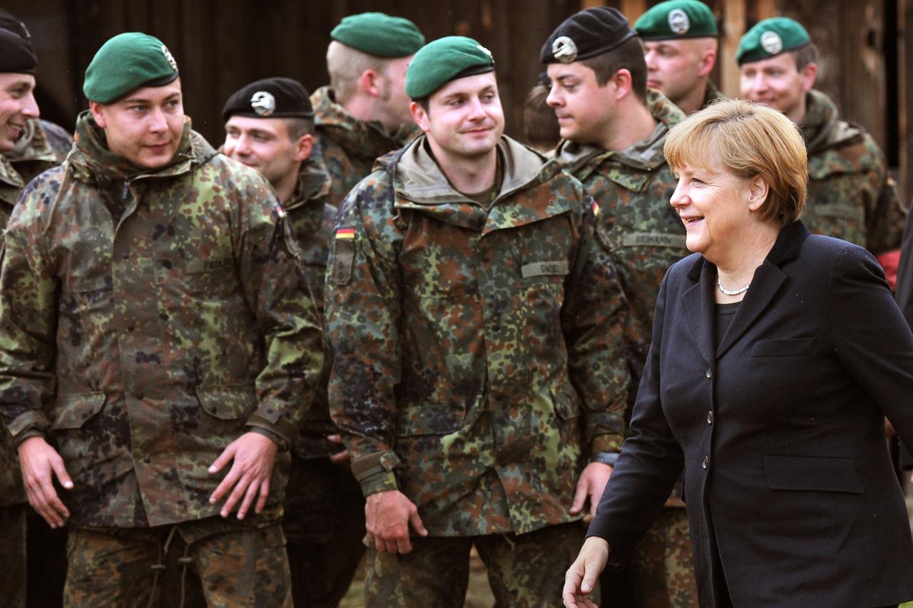 German Chancellor Angela Merkel stands next to soldiers at the army training center in Munster, Germany, 10 October 2012. The chancellor is informing herself about the state of training at the largest facility of the army. Photo: JULIAN STRATENSCHULTE/DPA
