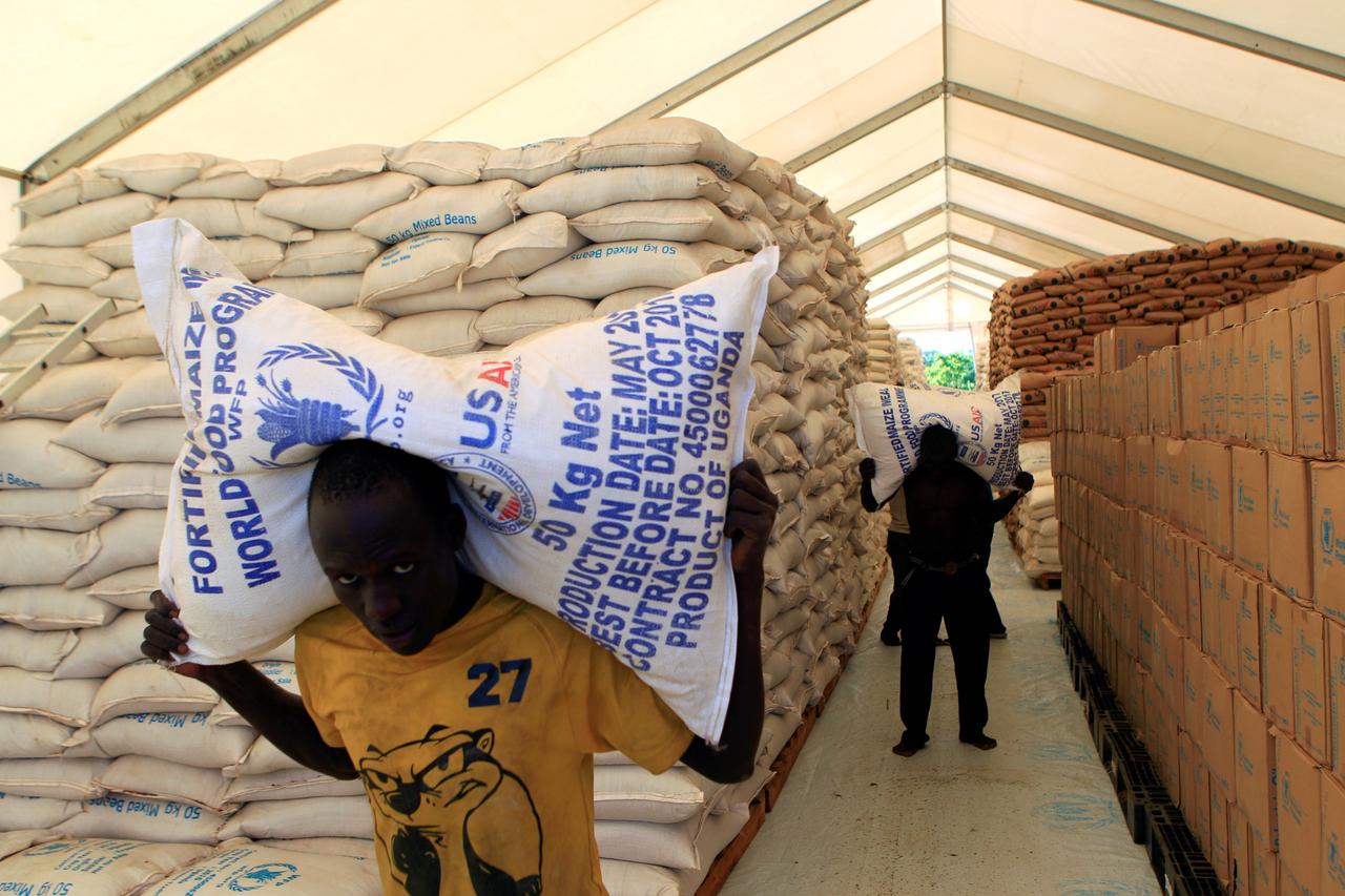 FILE PHOTO: People carry food from WFP for South Sudanese refugees at Palabek camp in Lamwo