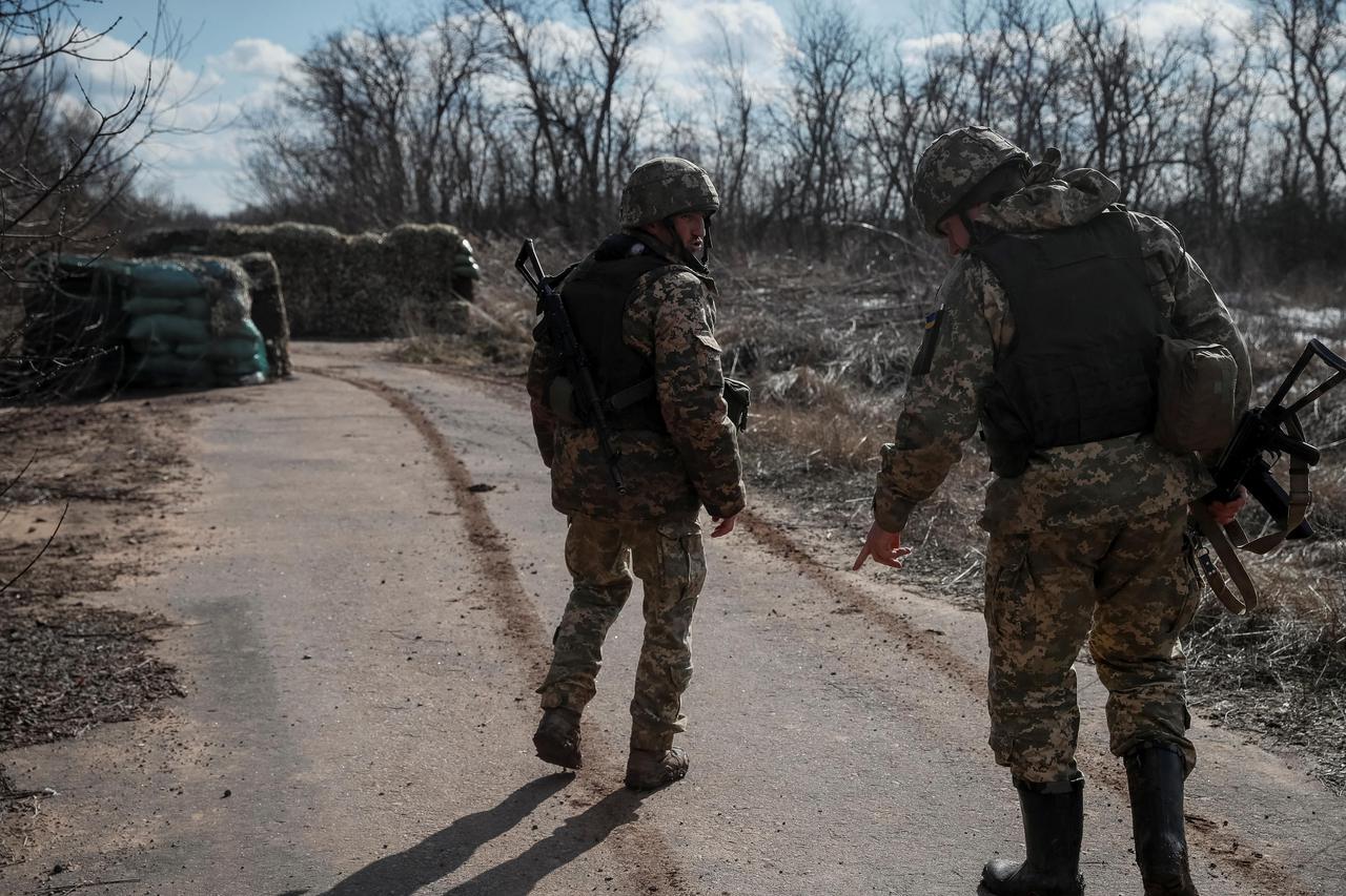 Ukrainian service members walk near the front line near the city of Novoluhanske