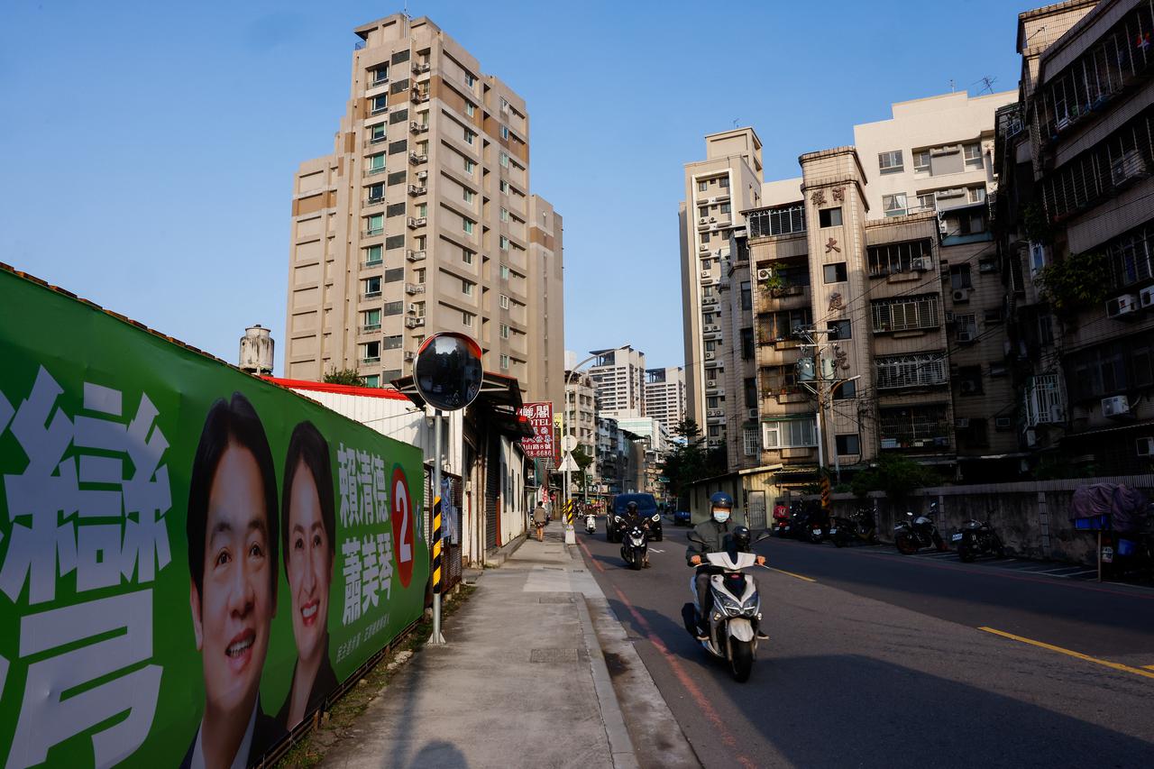 A person rides pass a campaign ad in Taipei