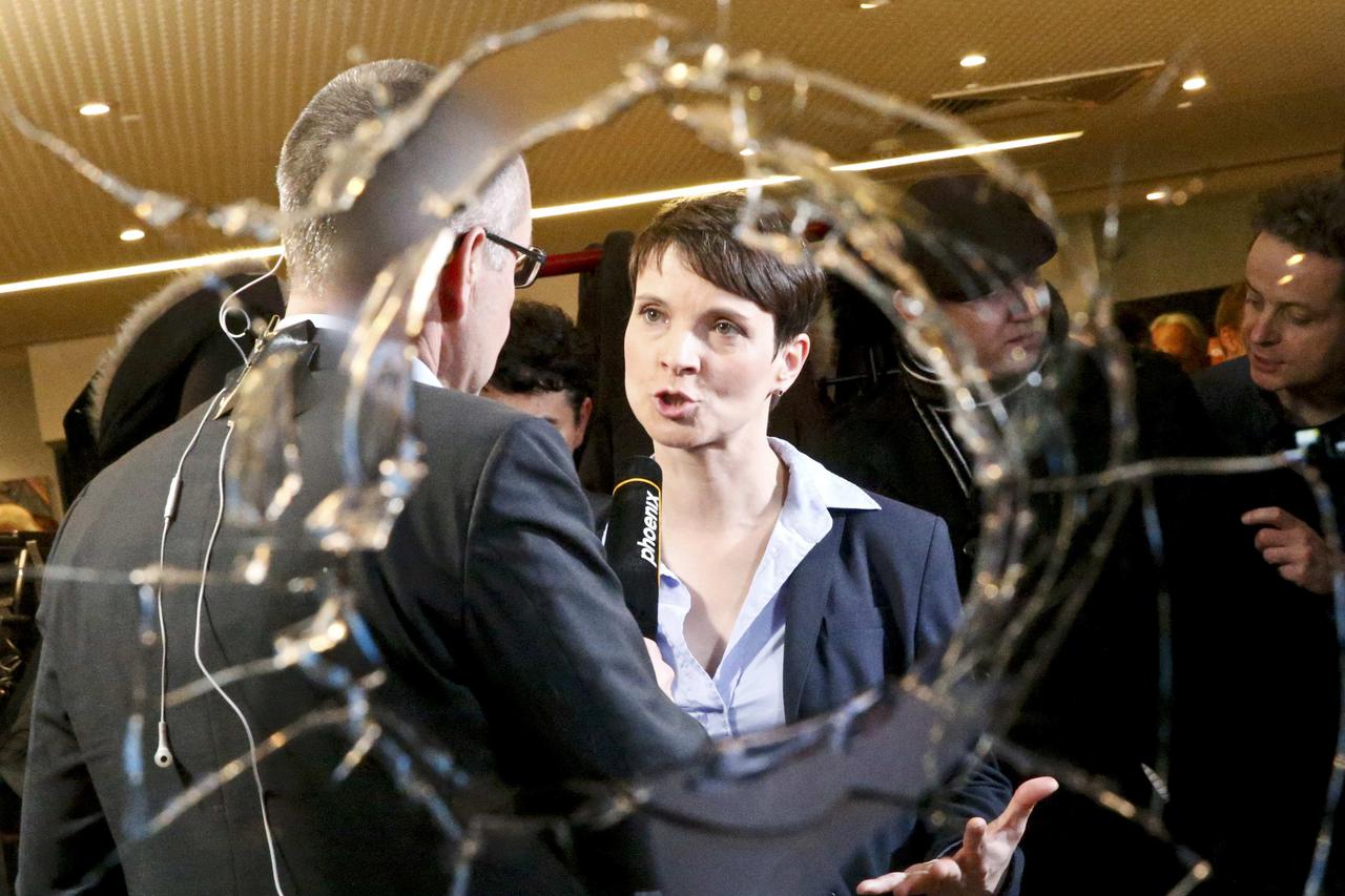 Frauke Petry, chairwoman of the anti-immigration party Alternative for Germany (AfD) is pictured through a broken window after first exit polls in three regional state elections at the AfD party's election night party in Berlin, Germany, March 13, 2016.  