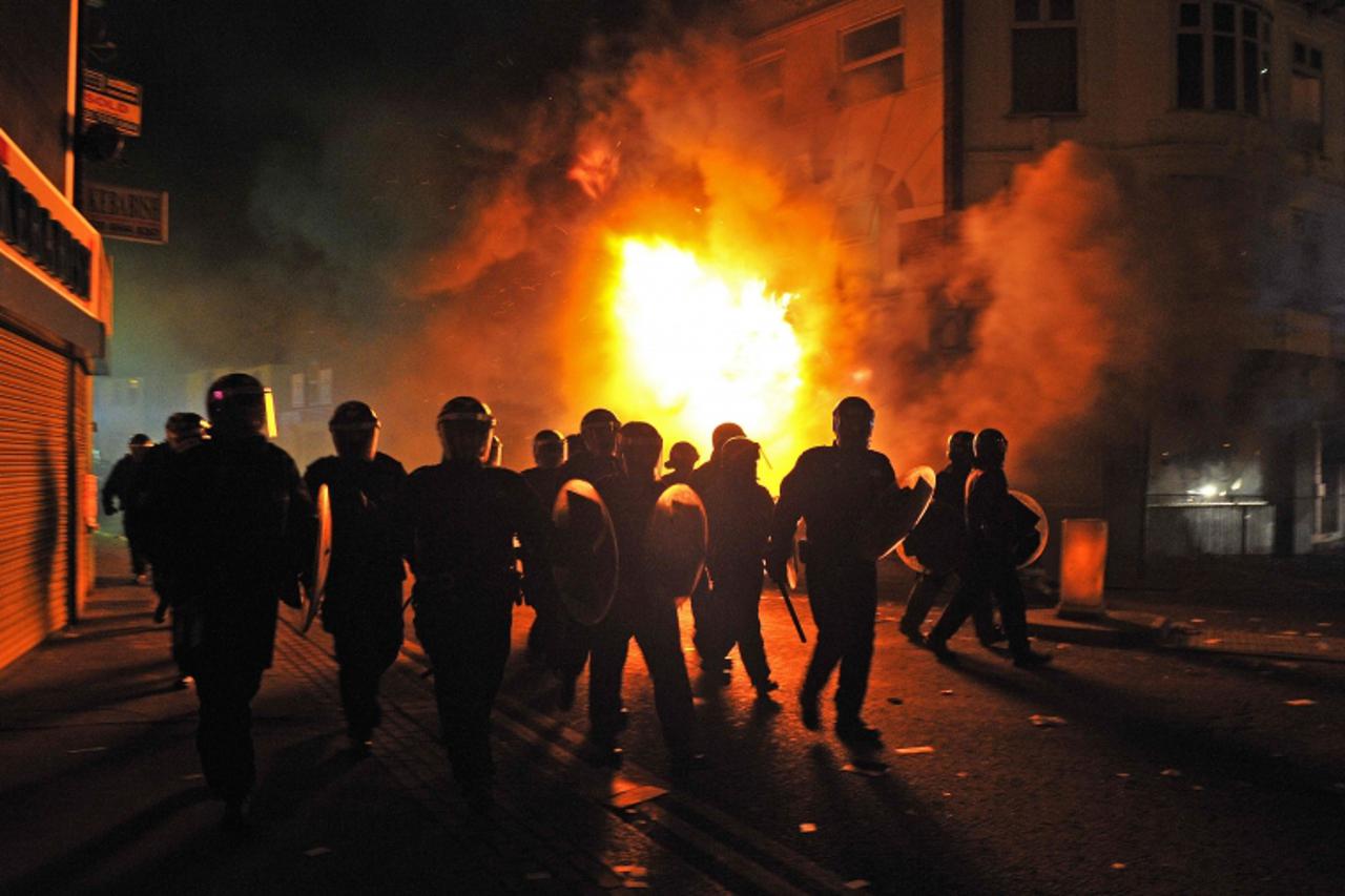 \'British riot police arrive in front of a burning building in Croydon, South London on August 8, 2011. Now in it\'s third night of unrest, London has seen sporadic outbreaks of looting and clashes bo