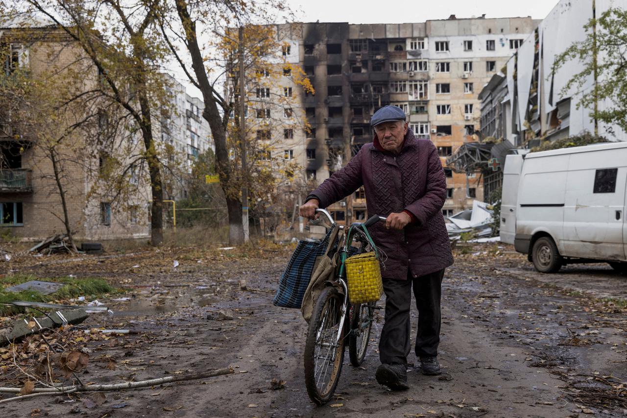 Local resident walks in front of damaged residential buildings in Avdiivka