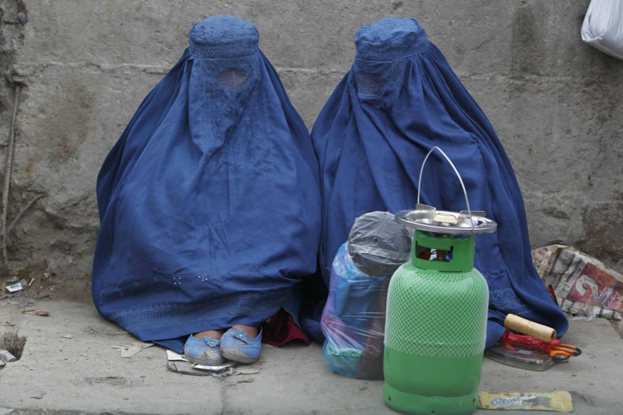 'Afghan women sit along a street as they wait for transportation in Kabul March 19, 2013.  REUTERS/Omar Sobhani (AFGHANISTAN - Tags: SOCIETY)'