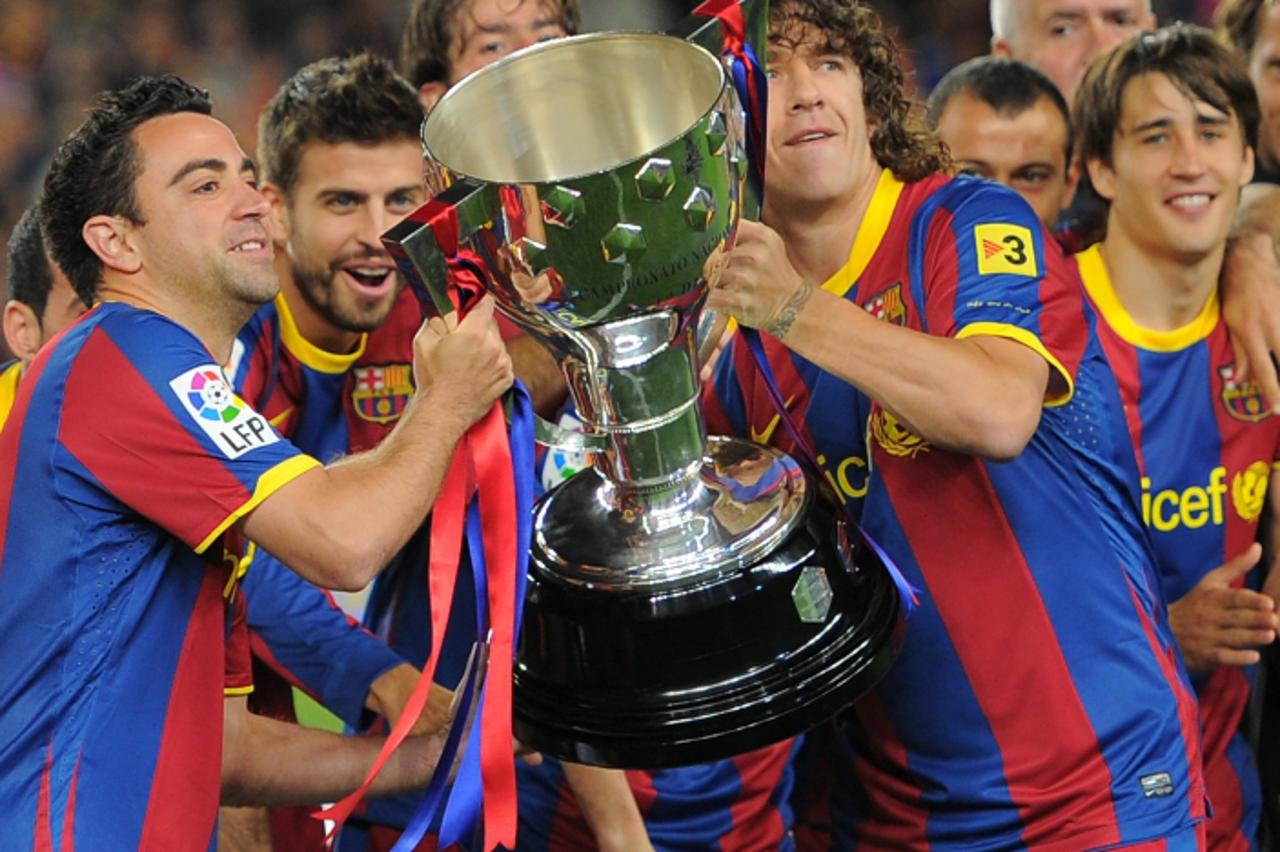 'Barcelona\'s Carles Puyol (R) and teammates raise the Spanish league title trophy as they celebrate after their Spanish League football match between FC Barcelona and Deportivo on May 15, 2011 at the