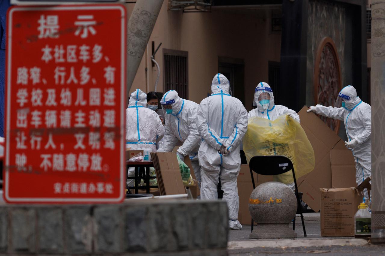 Pandemic prevention workers in protective suits collect trash in a locked-down residential compound as outbreaks of the coronavirus disease (COVID-19) continue in Beijing
