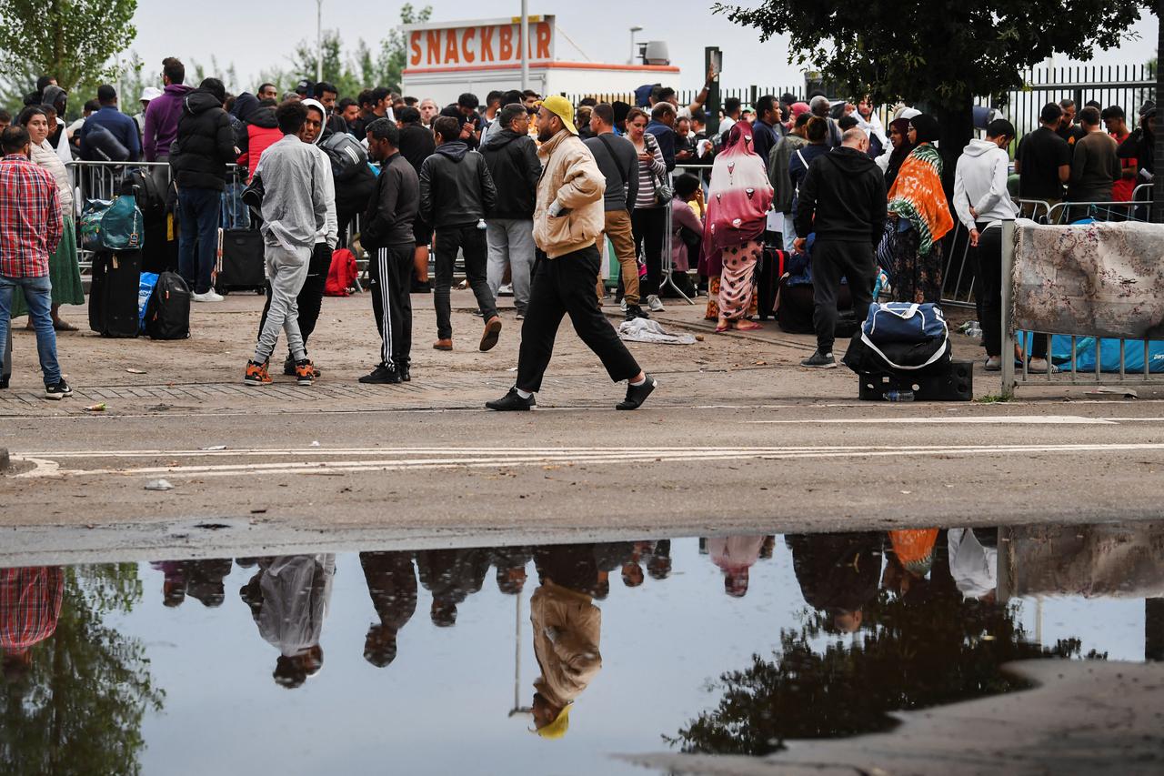 Refugees wait outdoors on the damp ground at the main reception centre for asylum seekers, in Ter Apel