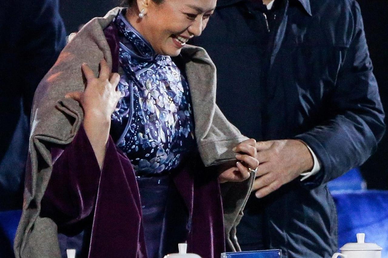 Russia's President Vladimir Putin (R) helps put a blanket on Peng Liyuan, wife of China's President Xi Jinping, as they watch watch a lights and fireworks show to celebrate Asia-Pacific Economic Cooperation (APEC) Leaders' Meeting, at National Aquatics Ce