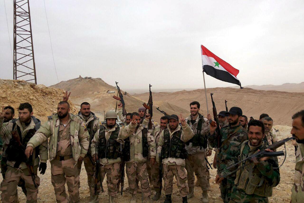 Forces loyal to Syria's President Bashar al-Assad flash victory signs and carry a Syrian national flag on the edge of the historic city of Palmyra in Homs Governorate, in this file handout picture provided by SANA on March 26, 2016. Syrian government forc