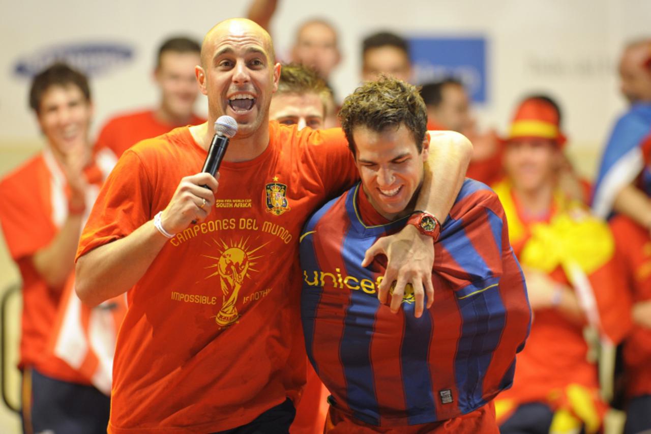 'Spain\'s goalkeeper Pepe Reina (L) holds Spain\'s midfielder Cesc Fabregas wearing Barcelona\'s jersey as they celebrate on a stage set up for the Spanish team victory ceremony in Madrid on July 12, 