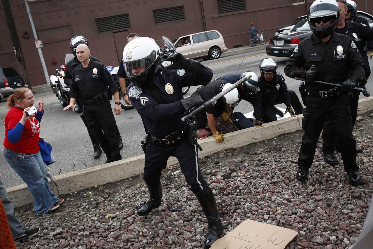 An LAPD motorcycle officer uses his baton to push back demonstrators during a rally against the Missouri grand jury's decision to not indict Darren Wilson for his fatal shooting of Michael Brown and the LAPD's fatal shooting of Ezell Ford, in Los Angeles,
