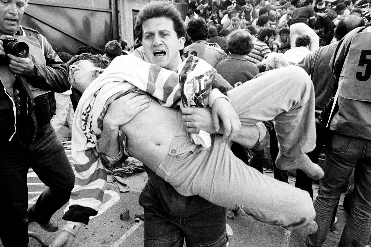 ATTENTION EDITORS - VISUALS COVERAGE OF SCENES OF DEATH AND INJURY    An injured soccer fan is carried to safety by a friend after a wall collapsed during violence between fans before the European Cup final between Juventus and Liverpool in this May 29, 1