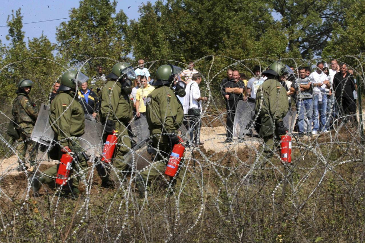 'Kosovo Force (KFOR) soldiers from Germany arrive with fire extinguishers at the closed Serbia-Kosovo border crossing of Jarinje September 27, 2011. Six Kosovo Serbs were injured in a shootout between