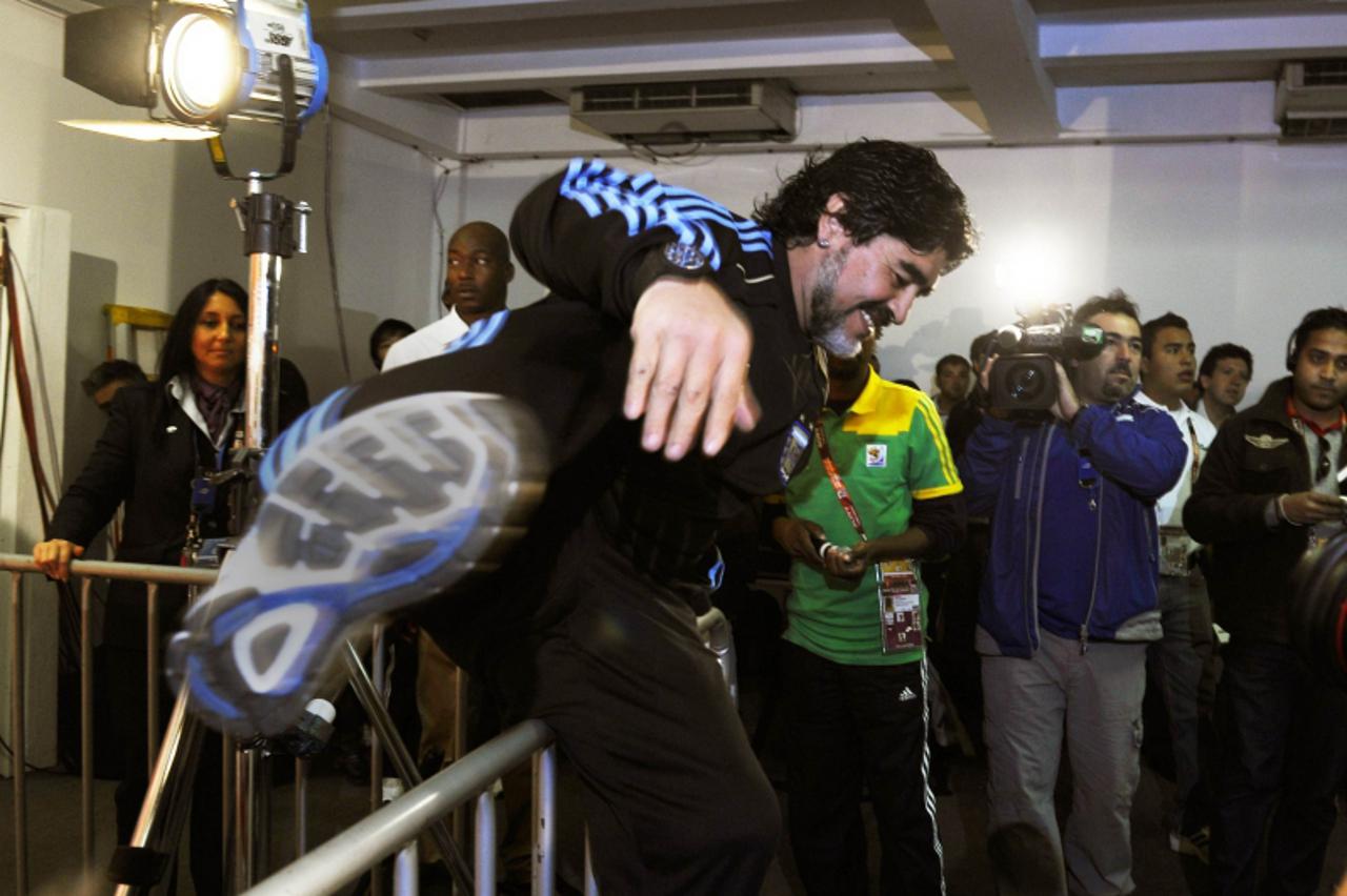 'Argentina\'s coach Diego Maradona jumps a barrier to embrace former Napoli teammate Salvatore Bagni during a press conference at Loftus Versfeld Stadium in Pretoria on June 26, 2010. Argentina will f