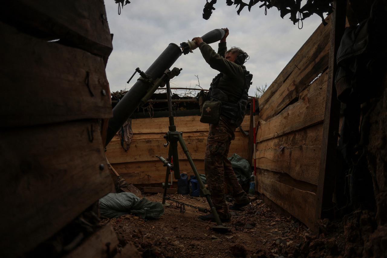 Ukrainian serviceman loads a shell into a mortar as he fires toward Russian troops at a position near a frontline in Zaporizhzhia region