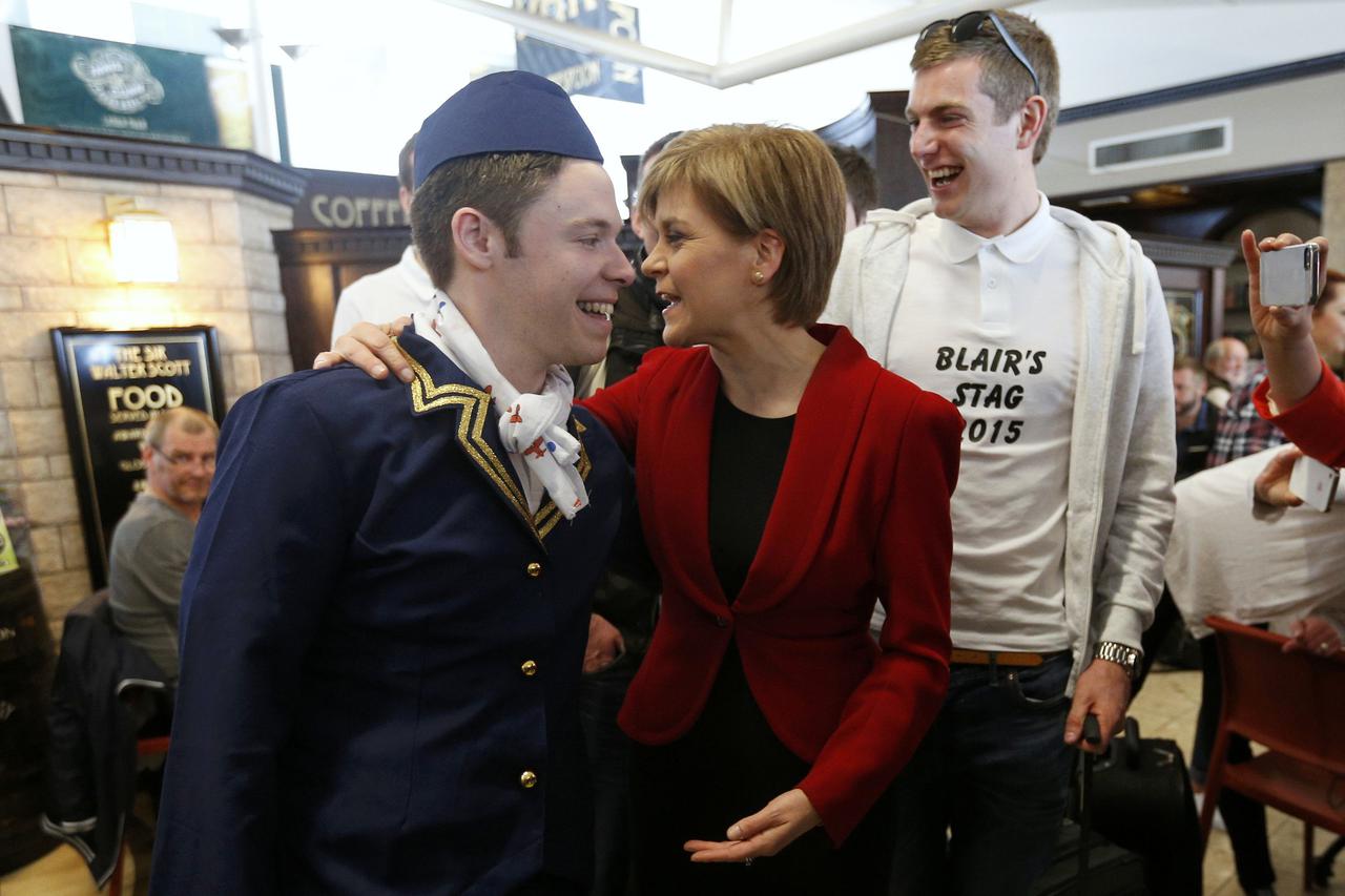 Nicola Sturgeon (C), leader of the Scottish National Party speaks with men going on a stag do, at Edinburgh Airport in Edinburgh, Scotland, Britain May 8, 2015. Prime Minister David Cameron won an emphatic election victory in Britain, overturning predicti