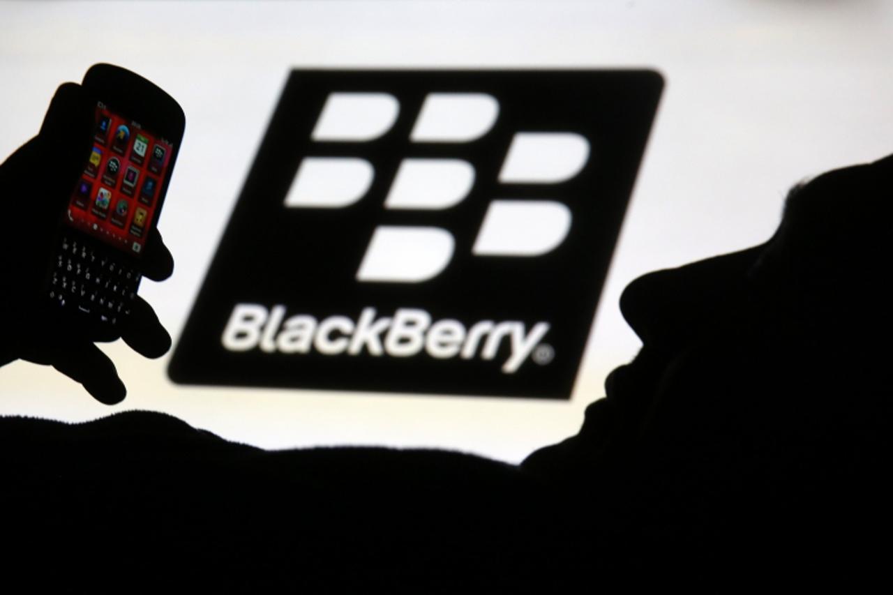 'A man is silhouetted against a video screen with the Blackberry logo as he pose with a Blackberry Q10 in this photo illustration taken in the central Bosnian town of Zenica, September 21, 2013. Black