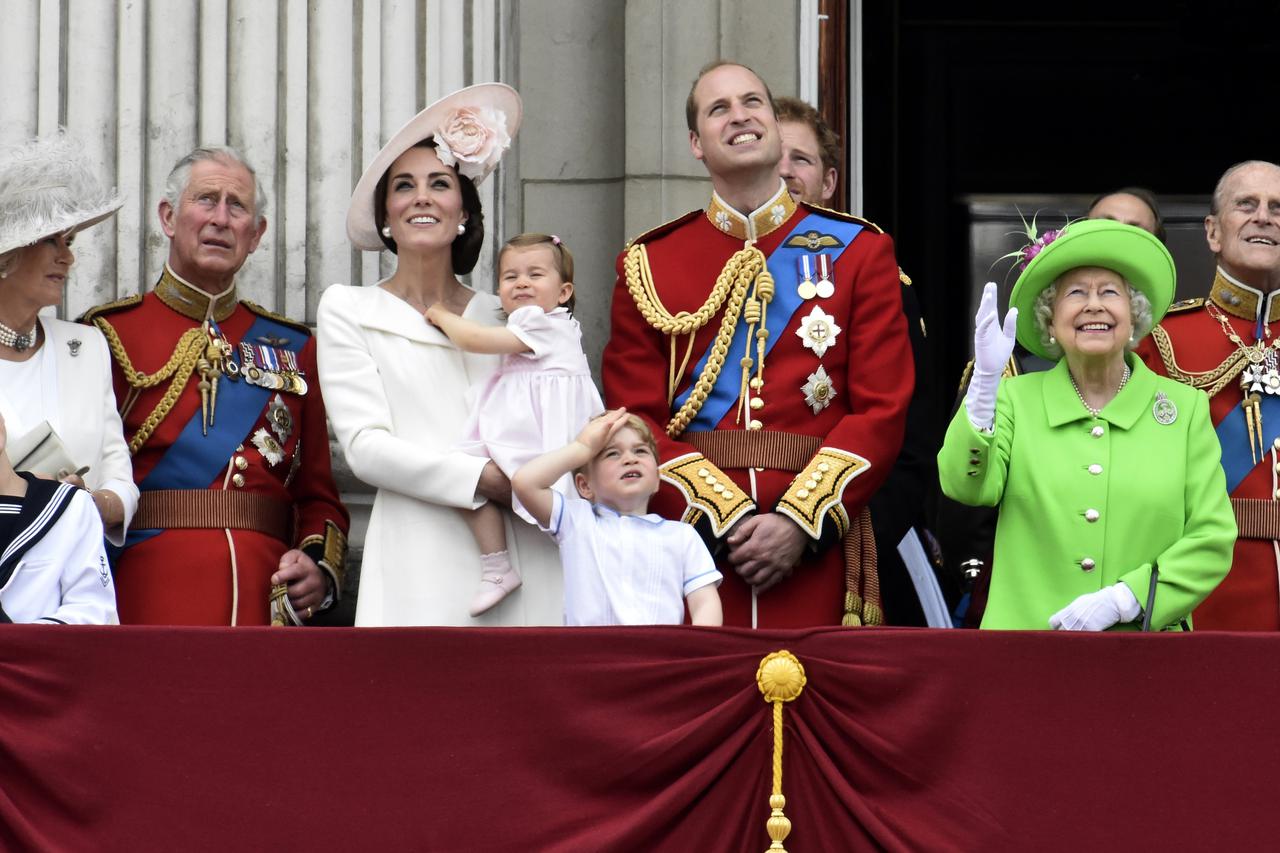 Members of the royal family, including Camilla Duchess of Cornwall, Prince Charles, Catherine, Duchess of Cambridge holding Princess Charlotte, Prince George, Prince William, Queen Elizabeth, and Prince Philip watch a flypast as they stand on the balcony 