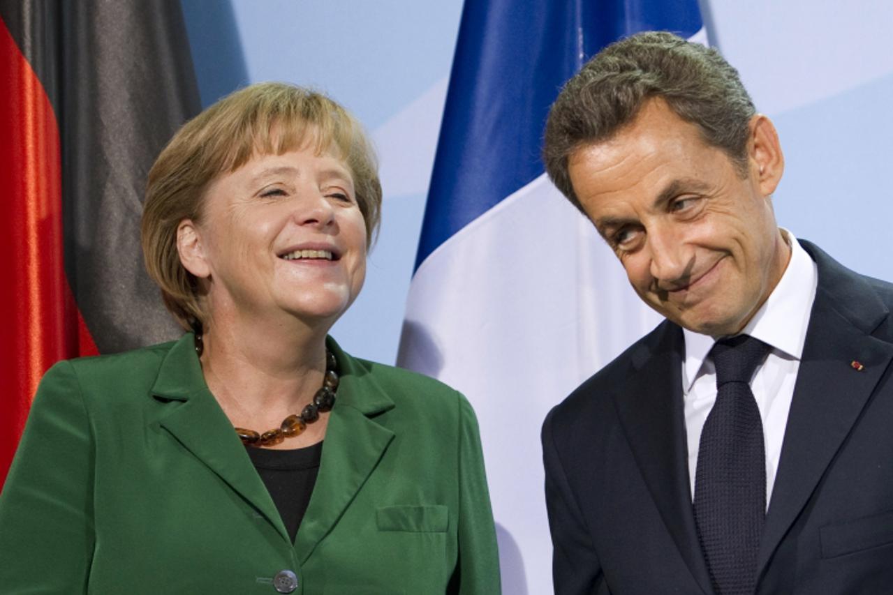 'German Chancellor Angela Merkel and French President Nicolas Sarkozy share a smile as they give a statement on October 9, 2011 at the Chancellery in Berlin following a key summit on steps to combat d
